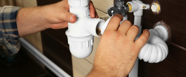 Hands of plumber assembling sink pipes, close up view