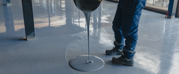 The worker applies gray epoxy resin to the new floor